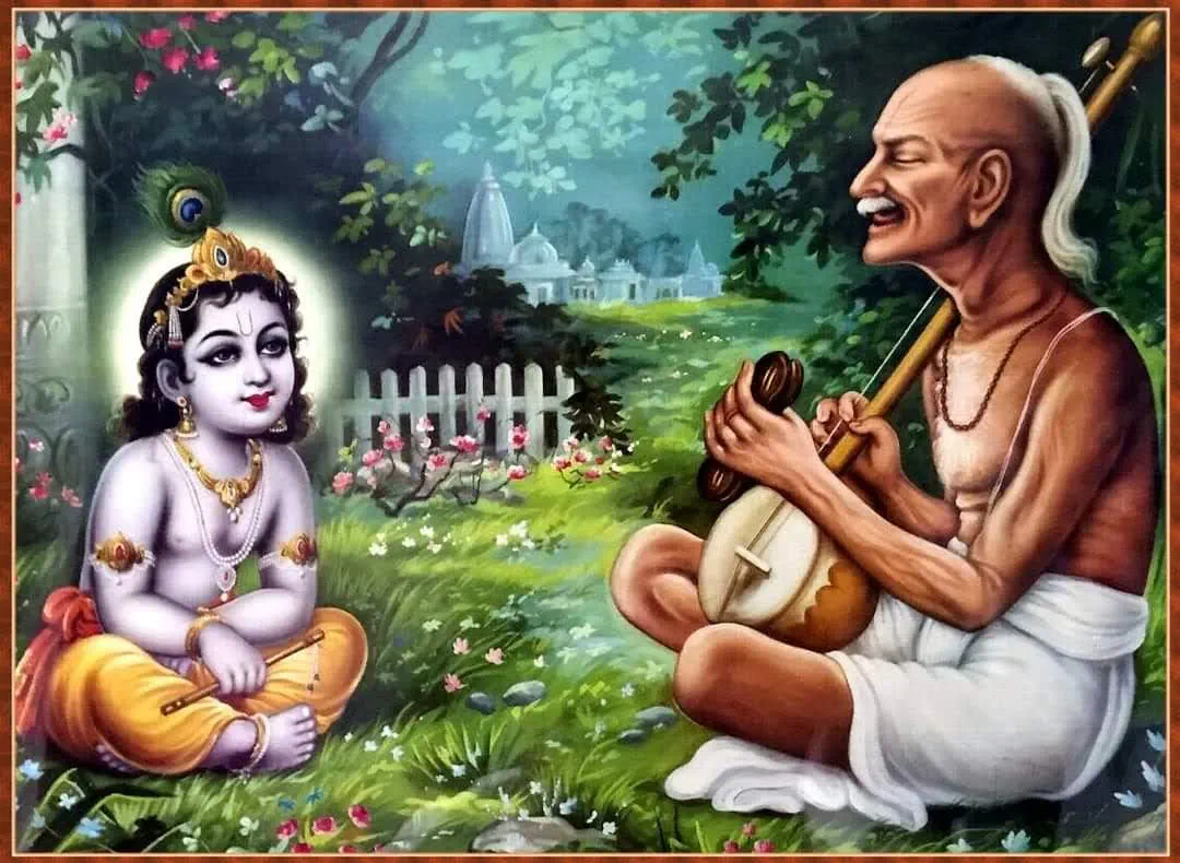 Surdas ji is depicted sitting cross-legged, deeply immersed in music as he plays his instrument with devotion. Beside him sits little Krishn…